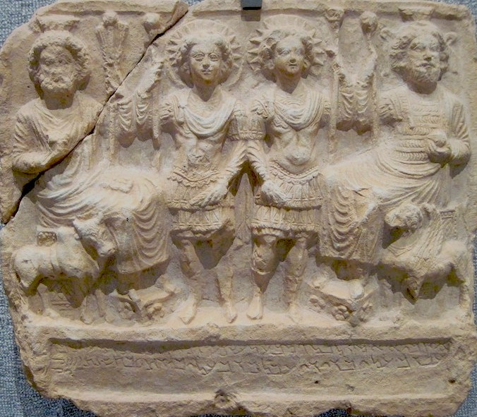 Reliéf v řecko-římském stylu z Palmýry v Sýrii, 121 n. l., vápenec, výška 47 cm, uloženo v Musée des beaux-arts de Lyon, Francie. Podle nápisu jsou zobrazeni Bêl, Ba’alsamin, Yarhibôl a ‘Aglibôl. Vyobrazení převzato z https://fr.wikipedia.org/wiki, autor fotografie: Marie-Lan Nguyen. Pohled na západní obzor, takže výjev je obrácený, nežli bývá zvykem. Vlevo na jihu, kde zapadá Slunce v zimě, je bůh zimní poloviny roku Bél (ugaritský Baal) se svojí zvířecí podobou býkem. Po levici má Aglibola ,tele pána‘ s novolunním měsíčním srpkem pod svatozáří. Vpravo je Baalshamin ,Baal zručný‘ se svojí zvířecí podobou okřídleným lvem. Po pravici má Jarchibola. Palmyra06