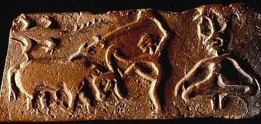 Tabulka s vytlačeným reliéfem, Harappa, uloženo v Harappa Museum, vyobrazení převzato z http://www.harappa.com. Vpravo přihlíží bůh jarní rovnodennosti Proto-Višnu, jak jeho svěřenec, mýtický Potomek, zabíjí svého nepoznaného otce v podobě bůvola. Přidáný krokodýl patrně naznačuje, že se děj odehrává při jarní rovnodennosti. Obet_byka_harappatablet